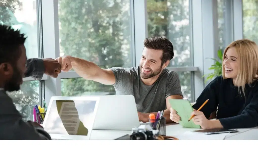 New Work im modernen Büro – Team arbeitet kreativ und feiert Erfolg mit Fist Bump