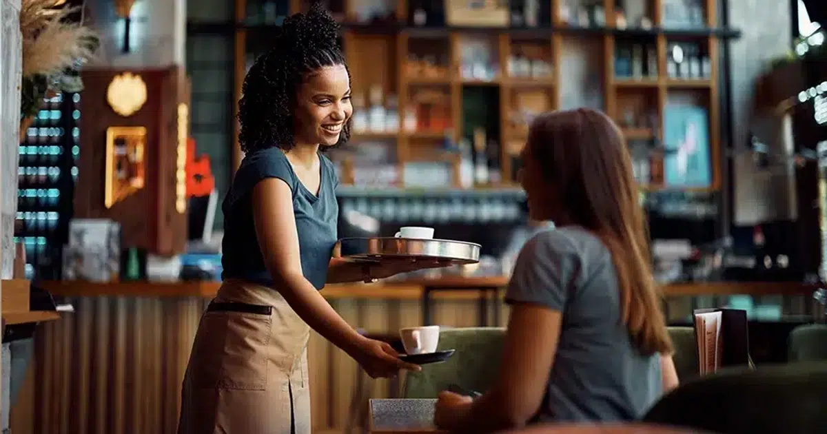Midijob im Café: Beschäftigte im Übergangsbereich profitieren von reduzierten Sozialabgaben bei einem Einkommen oberhalb der Minijob-Grenze. Midijob im Servicebereich: Kellnerin arbeitet in Teilzeit im Café