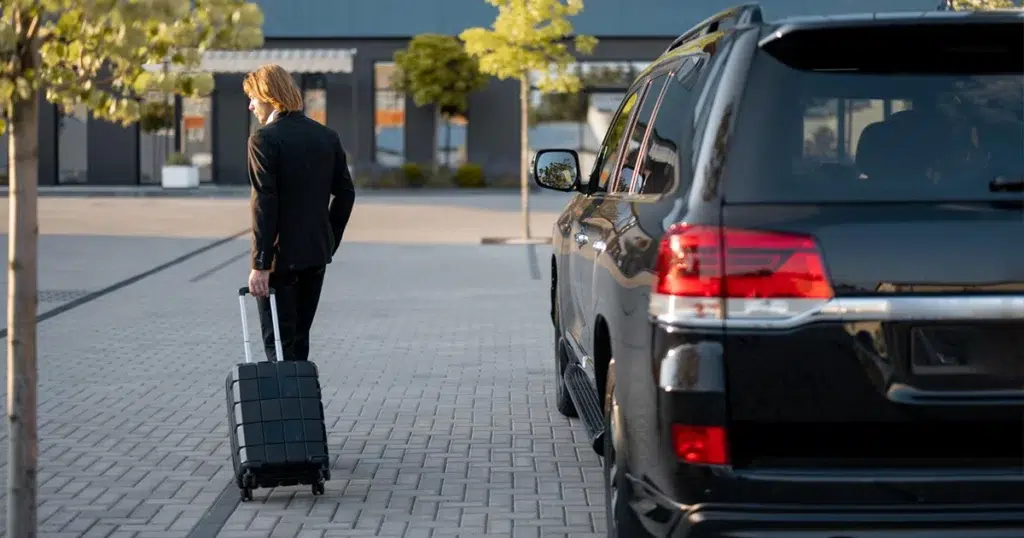 Pendlerpauschale: absetzbare Fahrten zur Tatigkeitsstätte Pendlerpauschale: Mann mit Koffer auf dem Weg zur Tagesstätte, neben ihm sein schwarzes Auto