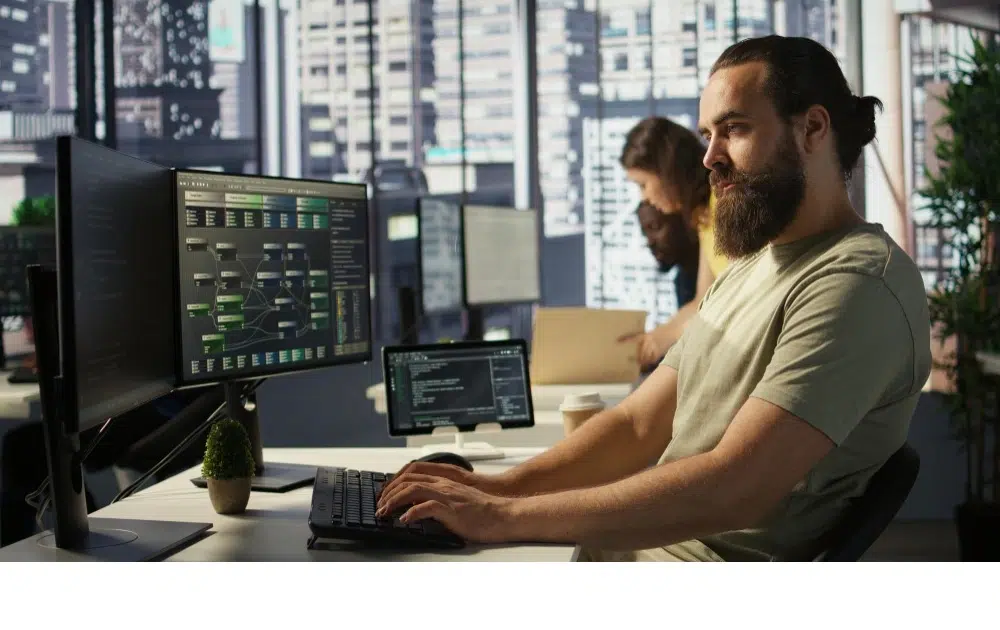 Factorial Alternative für HR-Software – Entwickler arbeitet an mehreren Monitoren im modernen Büro