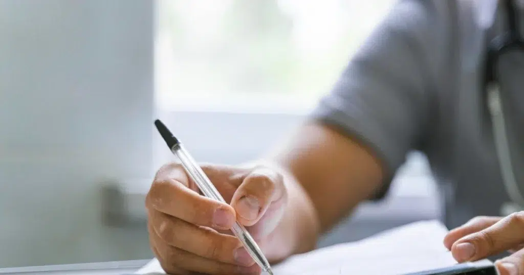 Krankschreibung rückwirkend – Formular korrekt ausfüllen Person füllt ein Formular zur Krankschreibung aus