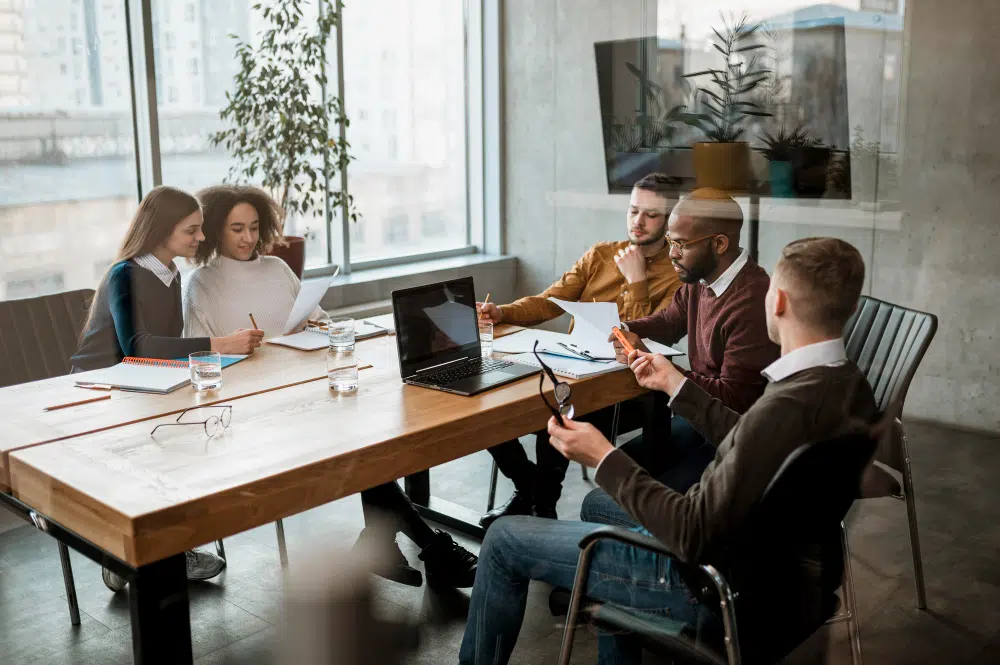 Kernarbeitszeit: Verbindlicher Zeitraum für Arbeitnehmer Kernarbeitszeit ist wichtig. Ein Team bespricht im Büro am Arbeitstisch über flexible Arbeitszeitmodelle und Kernarbeitszeit