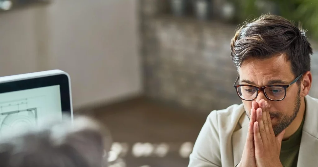 Besorgter Mitarbeiter sitzt im Gespräch nach einer ordentlichen Kündigung