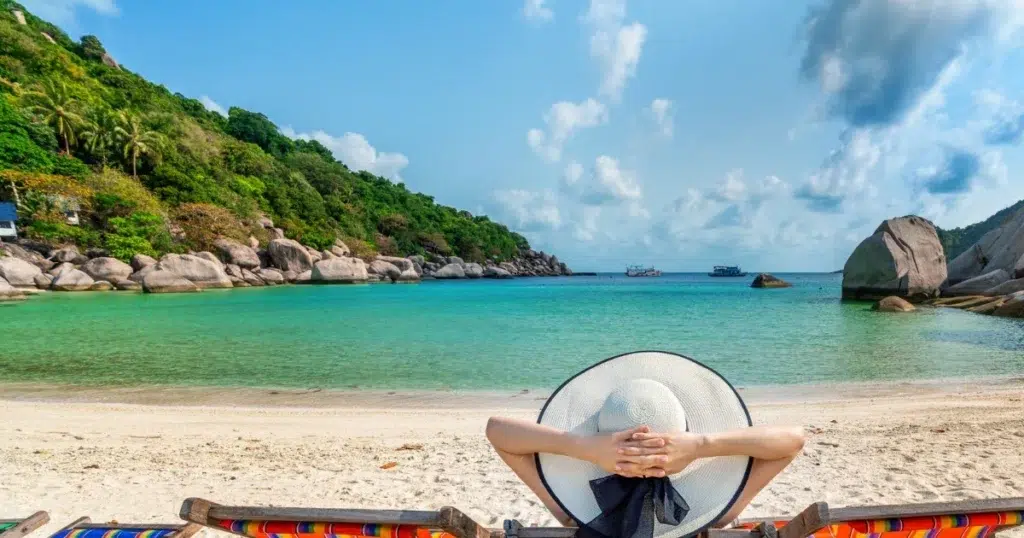 Urlaubsentgelt: Frau entspannt am Strand unter Sonnenschirm