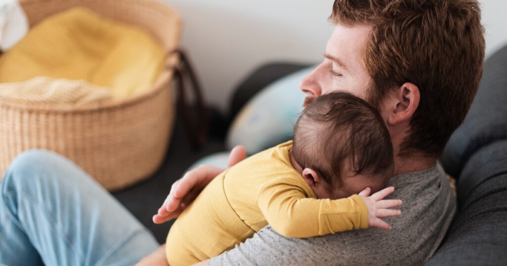 Vater hält sein Neugeborenes liebevoll im Arm während des Vaterschaftsurlaubs