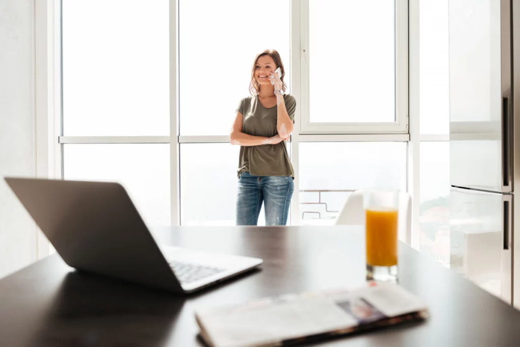 Gesetzliche Pausenzeit: Frau nutzt Ruhezeit zum Lesen Gesetzliche Pausenzeiten: Mitarbeiterin nutzt eine kurze Arbeitspause im Büro und telefoniert entspannt am Fenster