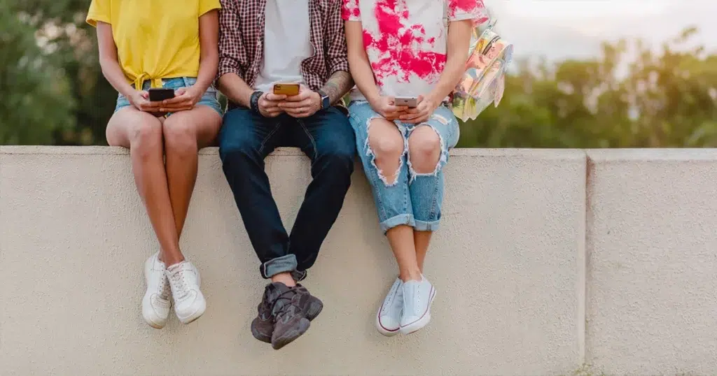 Generation Y kommuniziert und vernetzt sich im Alltag Generation Y in der Freizeit – vier junge Erwachsene sitzen gemeinsam im Park und unterhalten sich entspannt miteinander