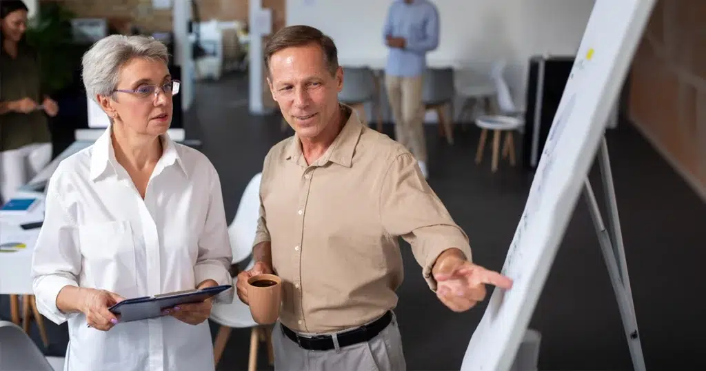 Generation Y: Merkmale, Werte und Einstellungen im Arbeitsleben Generation Y im Arbeitsumfeld – Mitarbeitende besprechen Inhalte gemeinsam am Flipchart im Büro und arbeiten kollaborativ zusammen