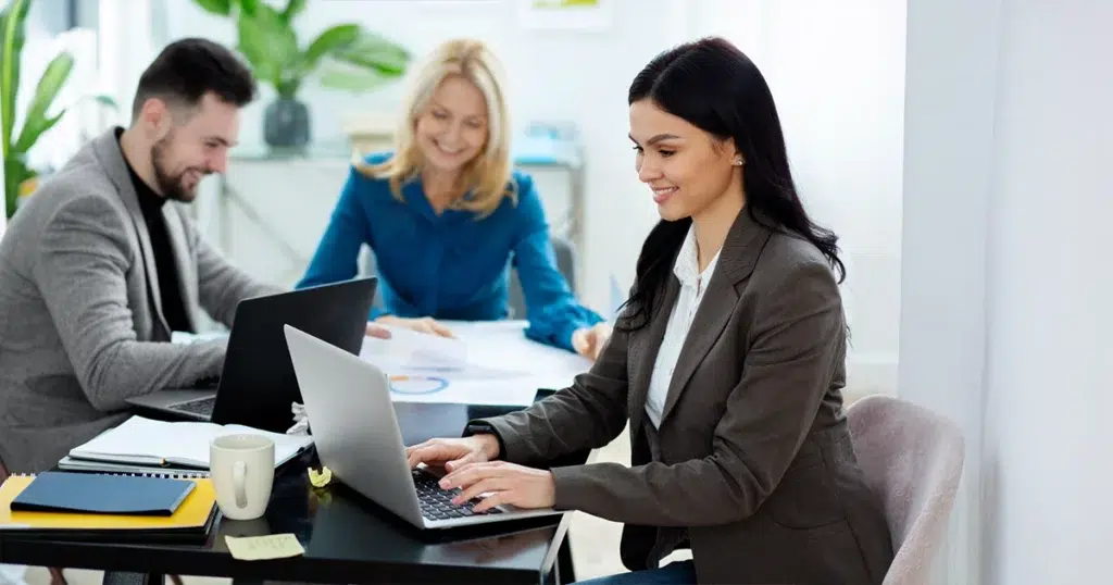 HRMS-System für digitale HR-Teamarbeit HRMS-System unterstützt ein HR-Team bei der gemeinsamen Bearbeitung digitaler Personalprozesse und Dokumente am Laptop