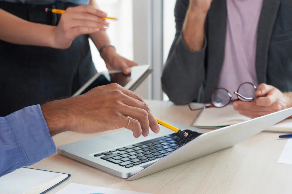 Abmahnung bei Arbeitszeitbetrug Drei Mitarbeitende aus dem HR besprechen eine Abmahnung bei Arbeitszeitbetrug am Laptop
